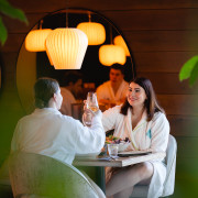 Twee dames proosten met wijn in badjas bij restaurant Senses tijdens wellnessdag.