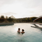 Twee gasten genieten in alle rust in de ochtend van het thermale buitenbad en het uitzicht over het zuid-limburgse heuvelland.