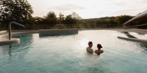 Twee gasten genieten in alle rust in de ochtend van het thermale buitenbad en het uitzicht over het zuid-limburgse heuvelland.