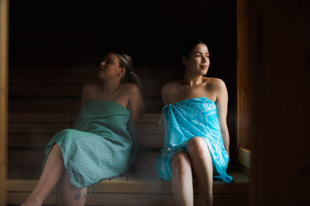 Twee vriendinnen met omgeslagen handdoek in sauna. 