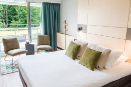 Hotelkamer Classic double met opgemaakt bed, stoeltjes en een plant.