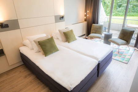 Hotelkamer Classic Twin met opgemaakt bed en zitje.