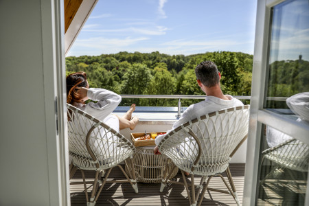 Koppel geniet op het balkon van de piramide suite met uitzicht over het groen.