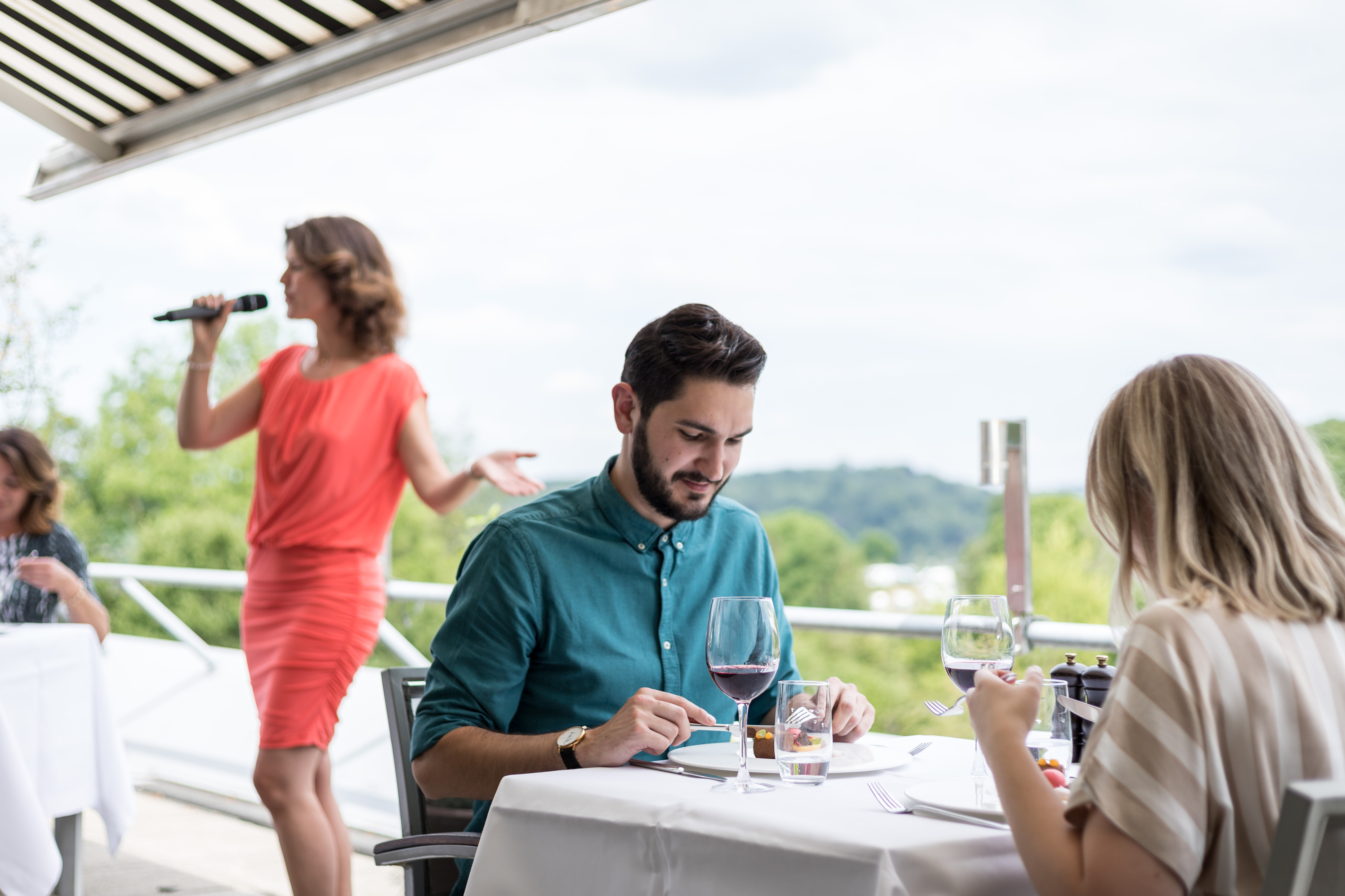 Vrouw zingt achter koppel dat dineert op het terras van Restaurant Pure met uitzicht over het Limburgse Heuvelland.