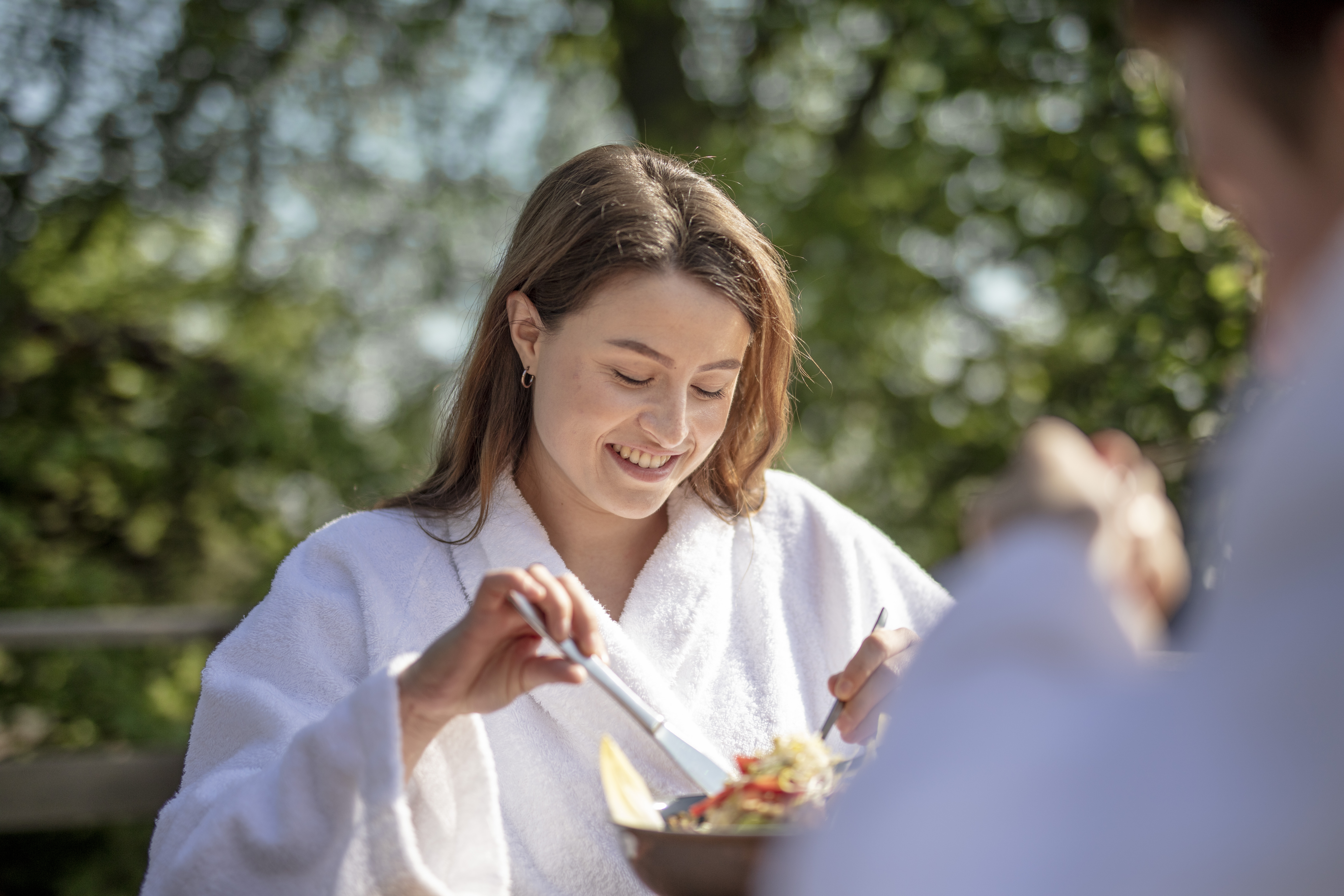 Vrouw dineert in badjas tussen de Limburgse natuur.