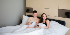 Koppel geniet met een koffie in bed in luxueuze wellness hotelkamer.