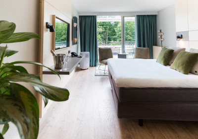 Classic Double Room met uitzicht over het bed, planten, champagne, stoelen en het privé terras.