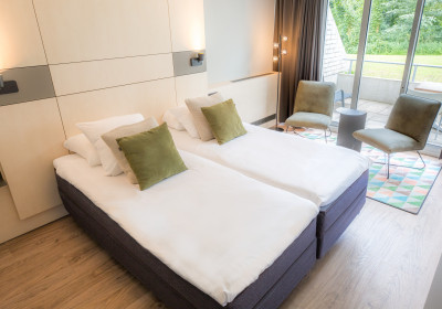 Classic Twin Room van het spa hotel in Limburg met bed, zitplek en privé terras.