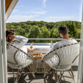 Man en vrouw zitten en ontbijten op het balkon van de Piramide Suite van het wellness hotel.