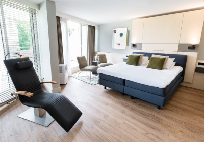 Superior Relax Room van het Thermen hotel met infraroodstoel, bed, zitplekje en privé terras.