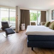 Superior Relax Room van het spa hotel van Thermae 2000 met bed, infraroodstoel en uitzicht over het privé en het Limburgse landschap.