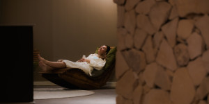 Vrouw in badjas ligt op relax stoel in de rustruimte met mergelstenen bij Thermae 2000.