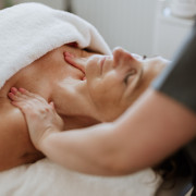 Dame geniet van gezichtsbehandeling en decolleté massage in de salon tijdens wellness dag. 